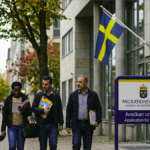 أشخاص يحملون أوراقاً قانونية أمام مبنى مصلحة الهجرة الرسمية لبدء معاملات اللجوء في السويد.