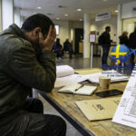 A stressed applicant reviewing an asylum rejection letter inside a Swedish Migration Agency office, illustrating common Sweden asylum rejection reasons.