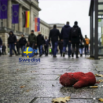 A discarded red mitten on a wet sidewalk in front of a European train station, representing the vulnerability of missing migrant children in Europe.