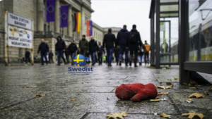A discarded red mitten on a wet sidewalk in front of a European train station, representing the vulnerability of missing migrant children in Europe.