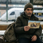 Why do some refugees choose to return home - A man sitting at Stockholm Central station holding a family photo.