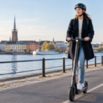 Woman wearing a helmet riding an electric scooter on a marked cycle path in a Swedish city.